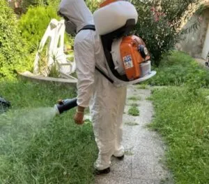 Operaio disinfestatore in tuta protettiva vaporizza prodotto chimico per la disinfestazione da mosche
