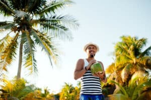 foto di un uomo con una noce di cocco sotto la pianta