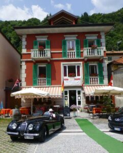 Immagine di un caffè allaperto in una città urbana come BusVilla Hotel & Resort una persona al tavolo sorseggia una bevanda, mentre unauto e un autobus passano accanto a una ruota di bicicletta Un paradiso urbano per rilassarsi e rifocillarsi